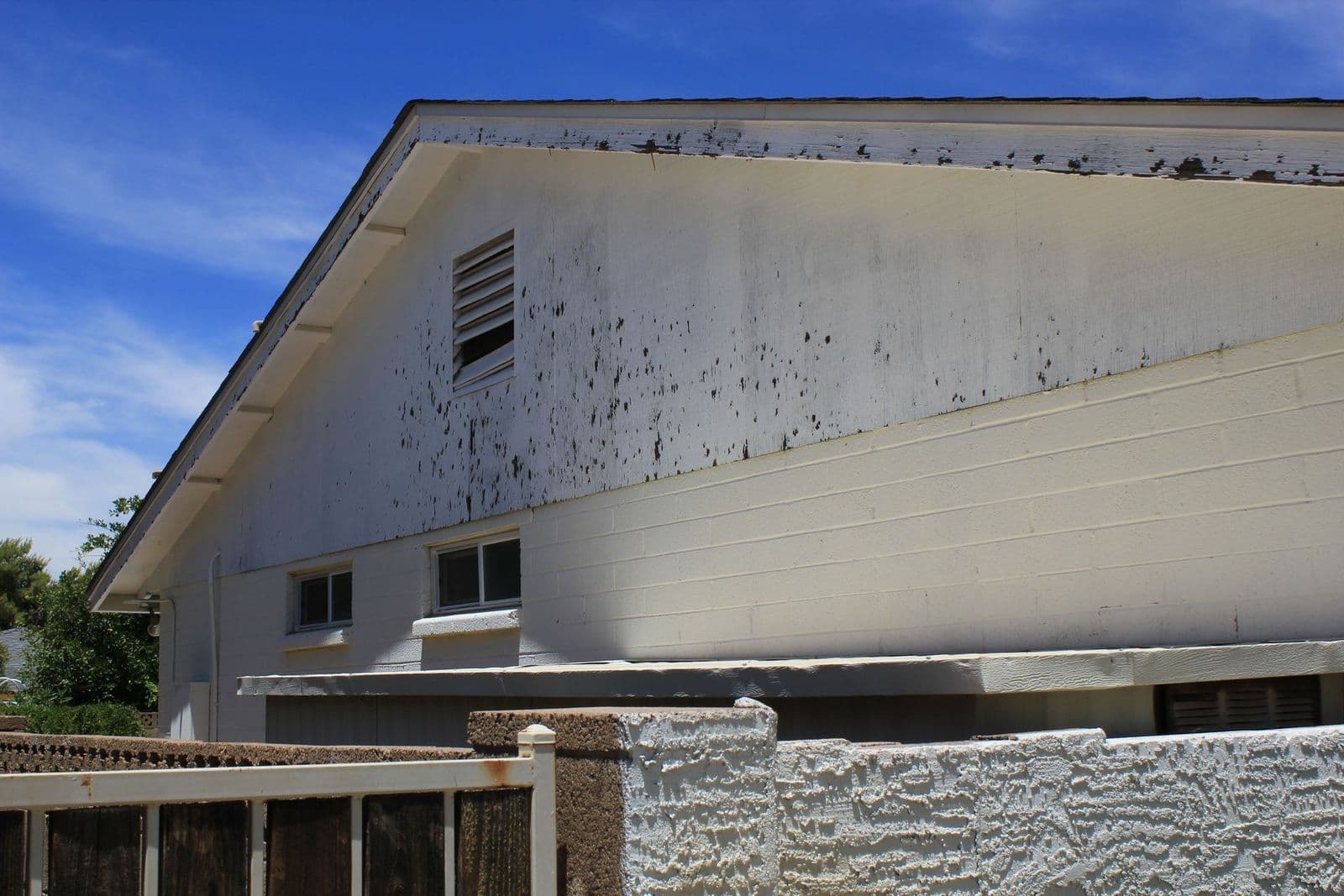 Older home with peeling exterior paint on its gable